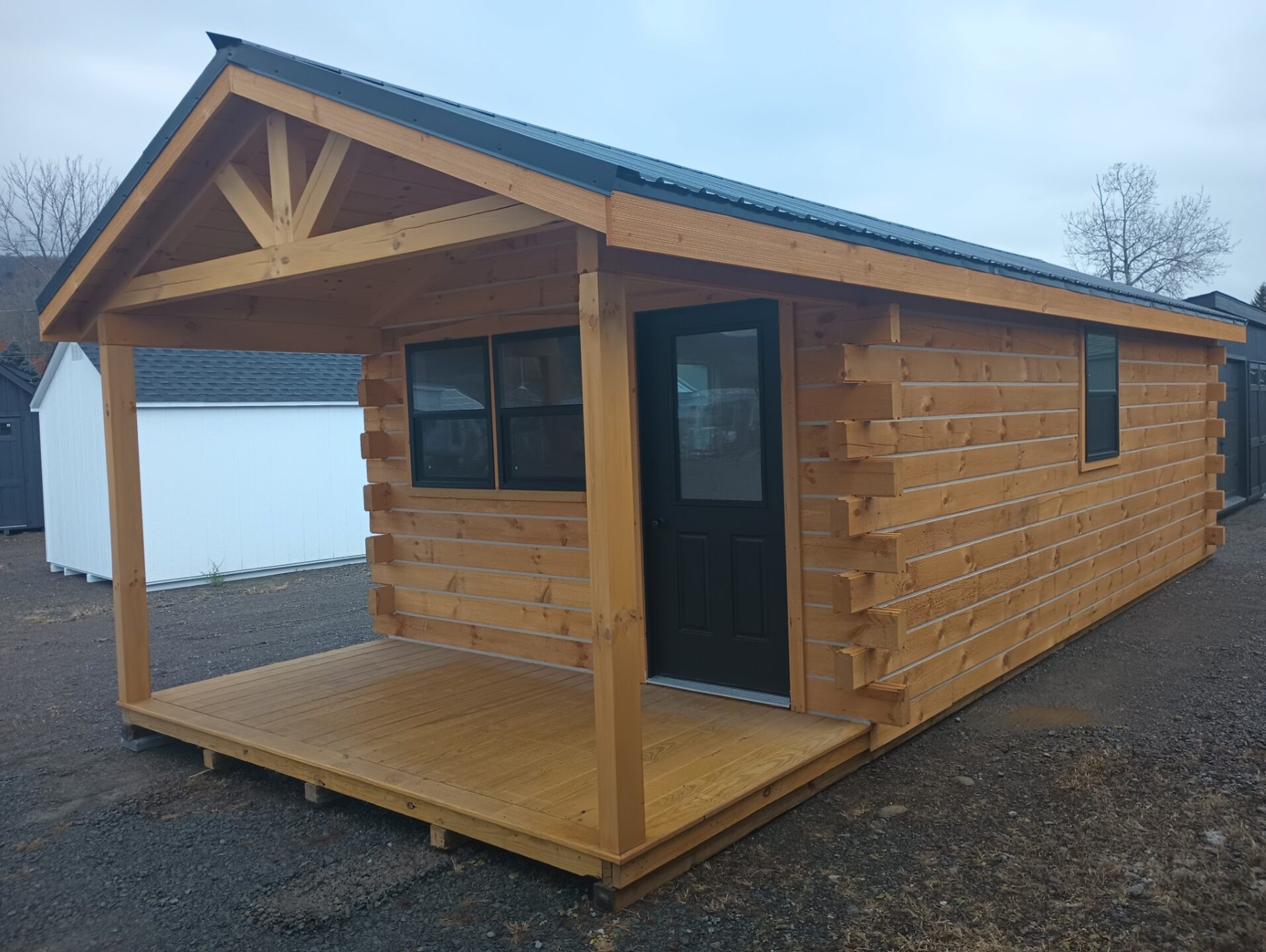 Small cabin with door with glass, many windows and timberframe front porch area
