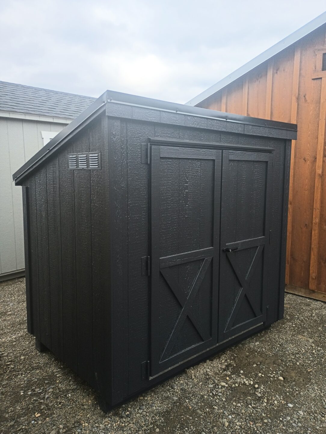 Small garbage can style shed with double doors and a slanted metal roof