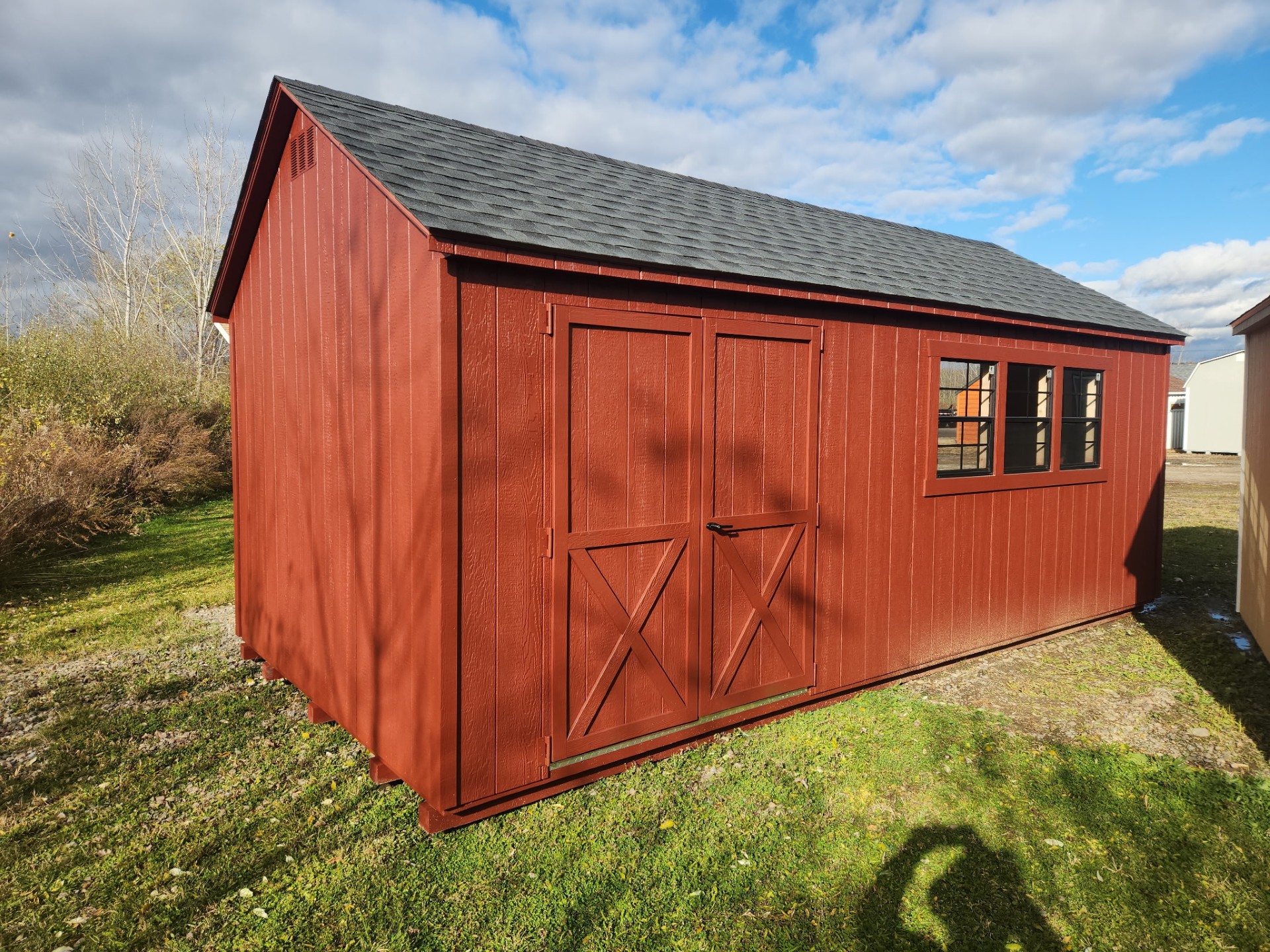 Red shed with peaked roof, double doors and three windows
