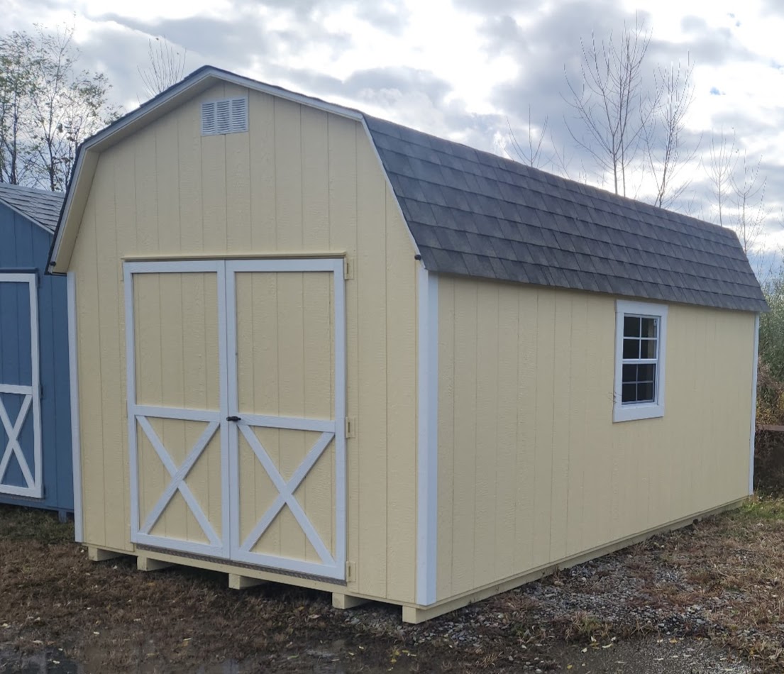 Cream color barn shed with double doors on end, shingles on roof and a window on either side