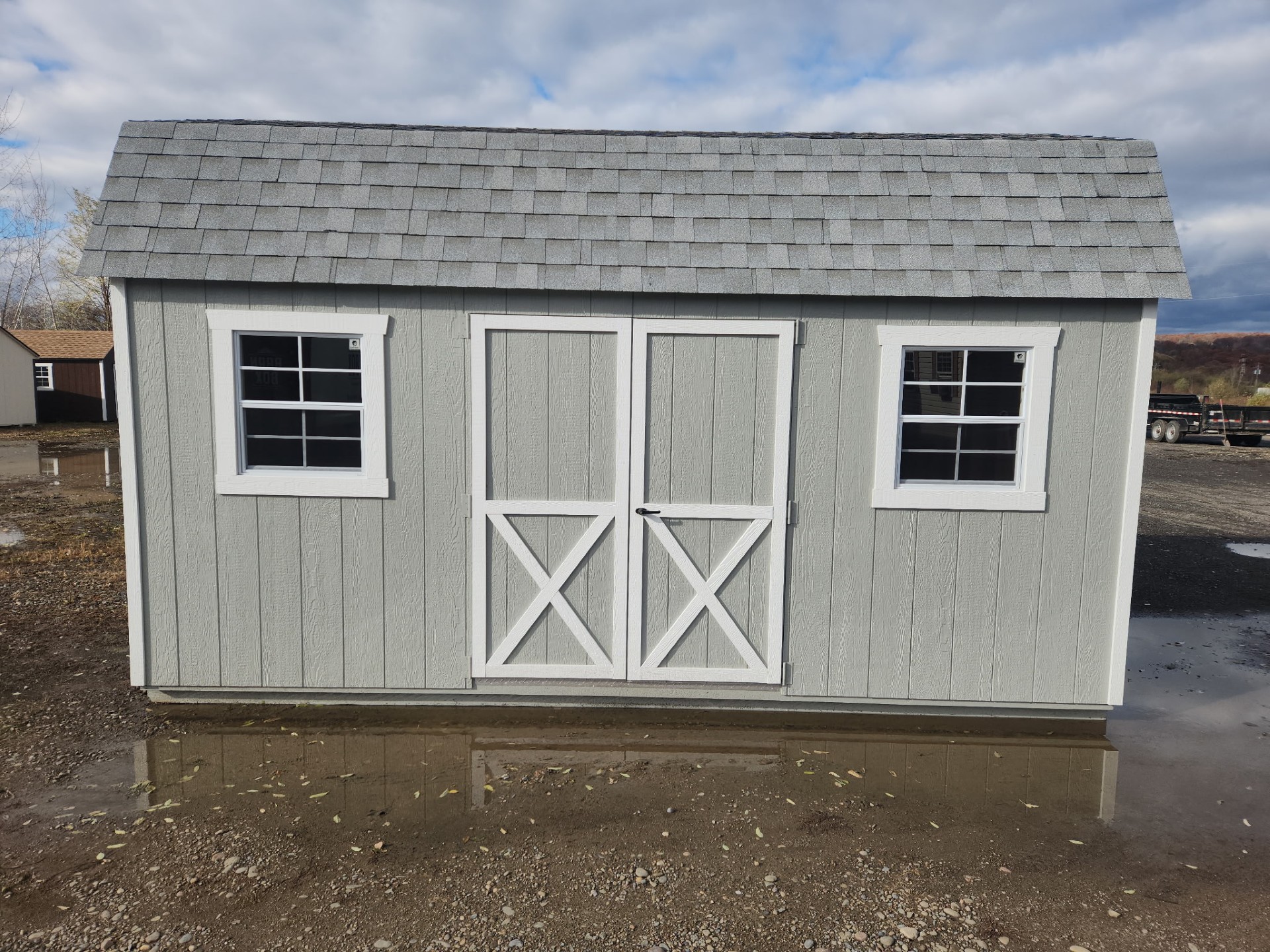 Small shed with double doors and two windows and shingles on the roof