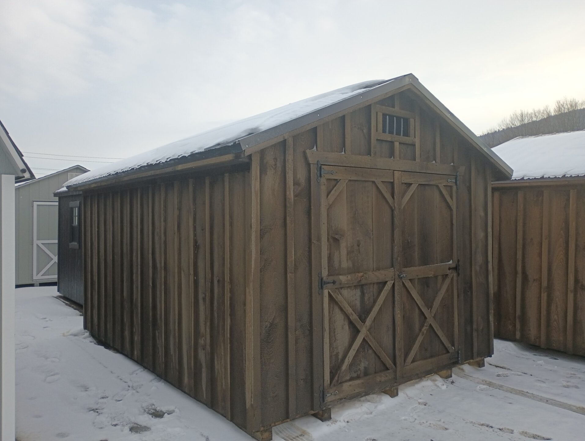 A frame shed with board and batten siding, double doors and metal roofing
