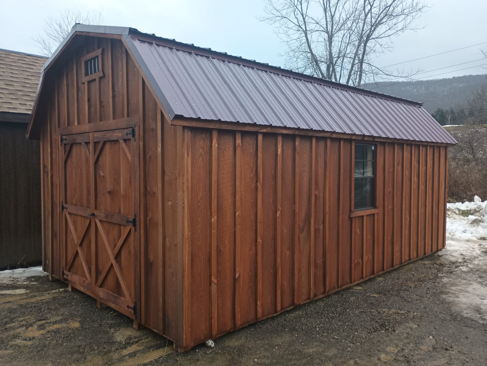 Large dutch style barn shed with double doors on either end, two windows and a metal roof