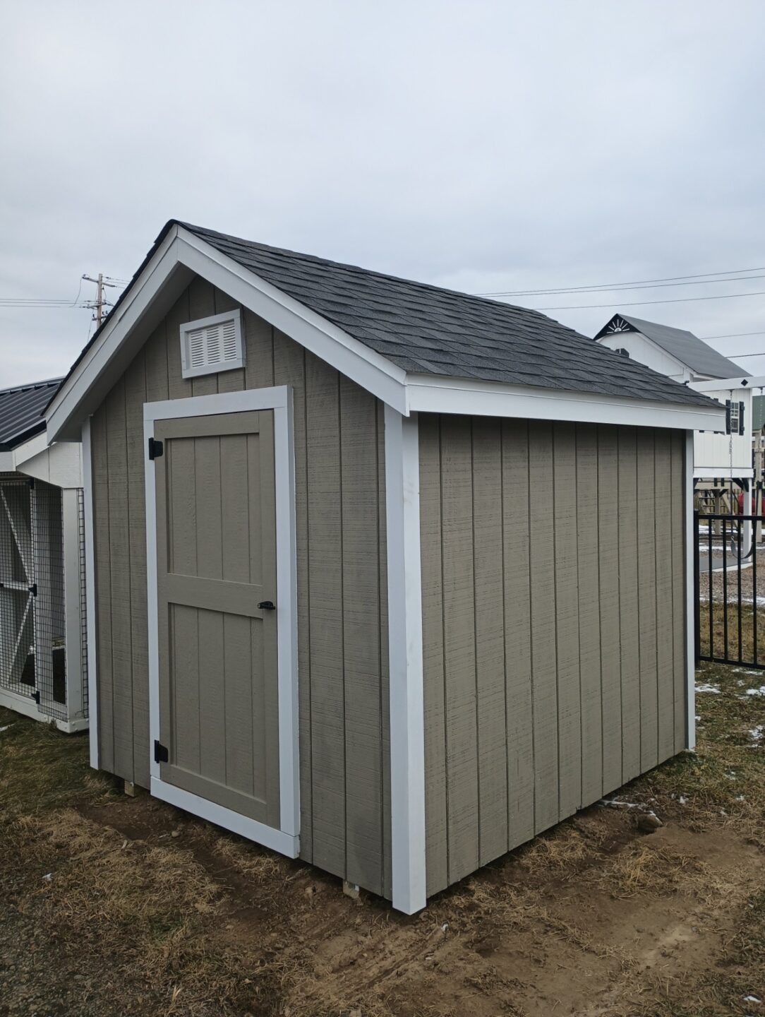 Small a frame style shed with single door, gable vents, shingled roof and painted siding